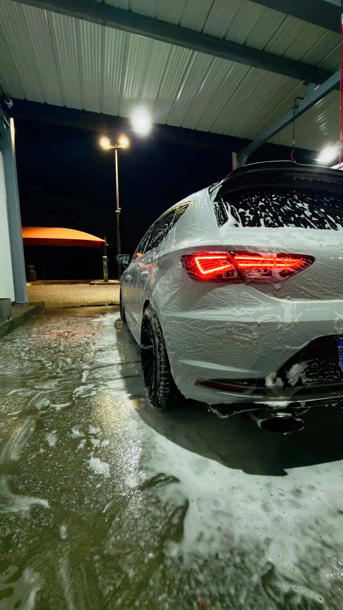 Cupra blanche couverte de mousse dans une station de lavage de nuit